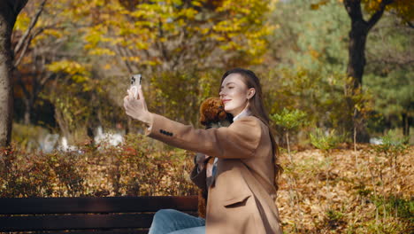 woman takes a selfie with her dog in an autumn park