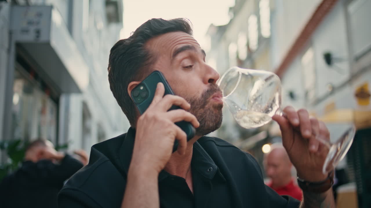 Angry macho sipping alcohol calling at street cafe closeup. Man drinking wine