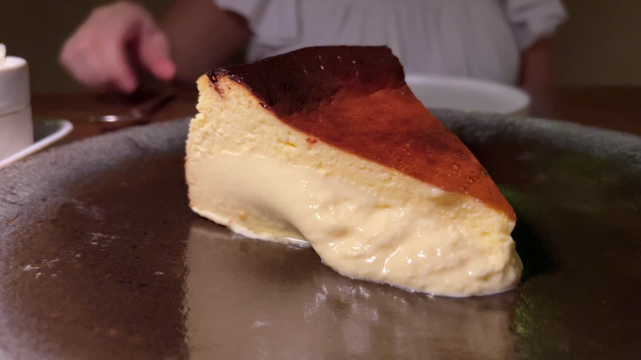 Cheesecake basca bruciata tradizionale spagnola, dessert dolce e cremoso su un piatto in un ristorante, ripresa 4K