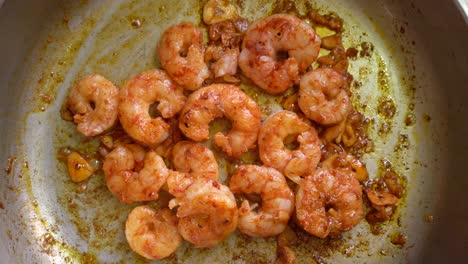 peeled shrimps with chopped garlic and spanish paprika cooking in a pan at the kitchen