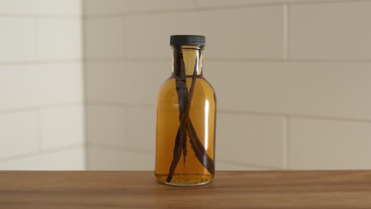 botella destilada de vainilla con granos de vainilla todavía en el líquido
