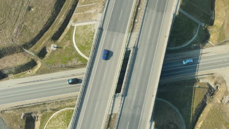 Vista-Aérea-De-Un-Puente-Sobre-Un-Cruce-Con-Poco-Tráfico-Y-Un-Coche-Verde-Destacándose