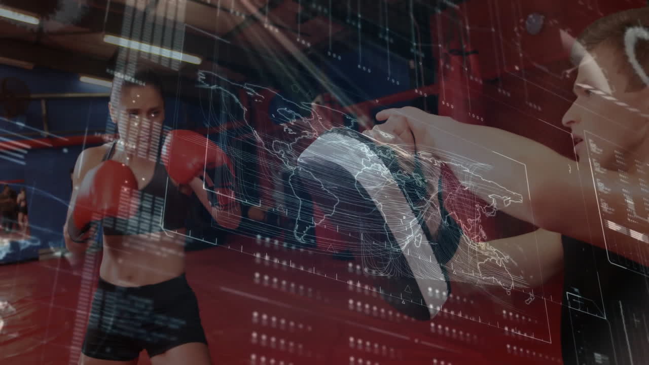 Female coach punching focus mitt in boxing gym, showing sports data overlay with world map readouts