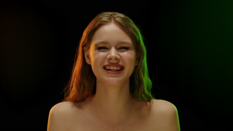 joyful young woman laughing with colorful studio lighting