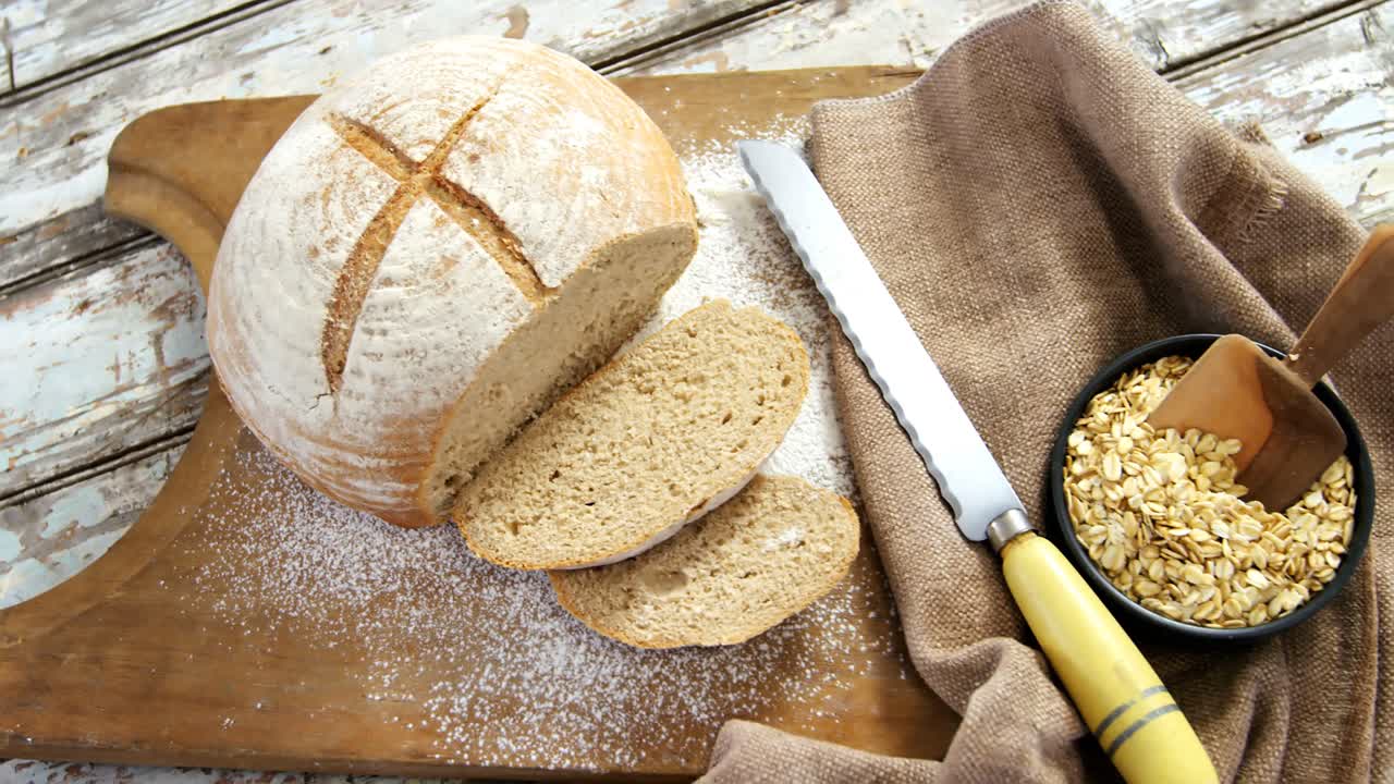 Bread loaf with knife and bowl of oats