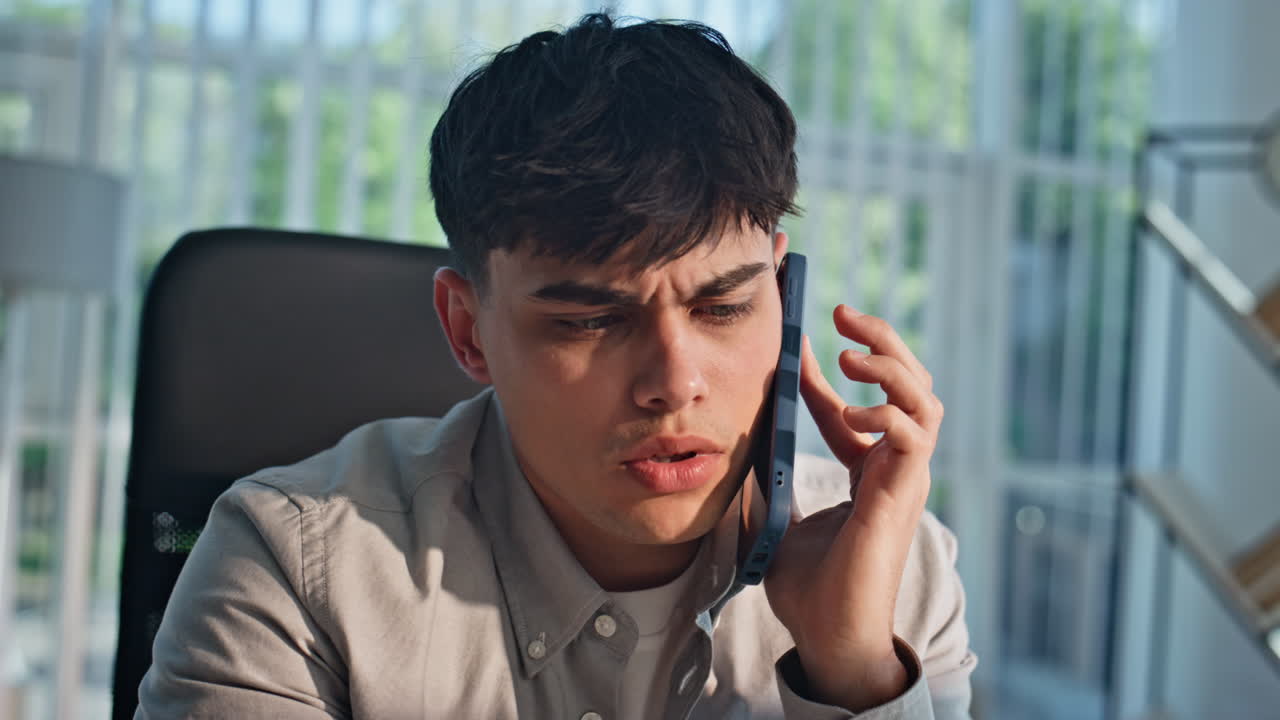 Worried manager talking smartphone hearing bad work news at workplace portrait