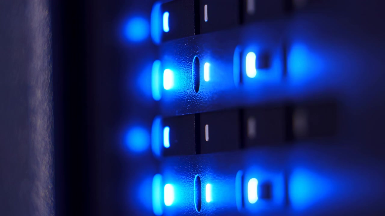 Close-up of a dark metallic surface with rows of warm glowing indicators on one side, creating a sleek abstract industrial look with soft reflections