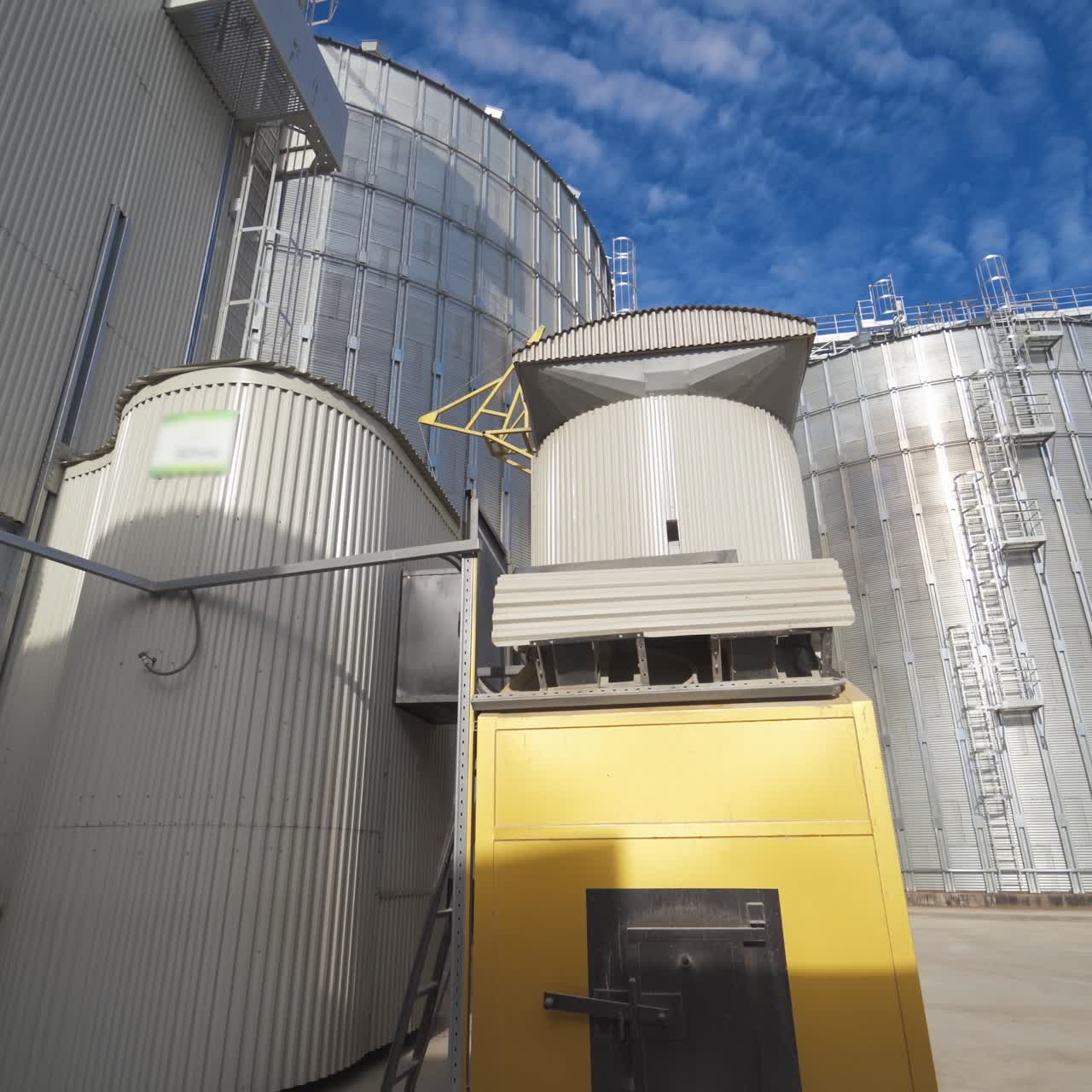 Modern Granary elevator. Silver silos on agro-processing and manufacturing plant for processing drying cleaning and storage of agricultural products, flour, cereals and grain