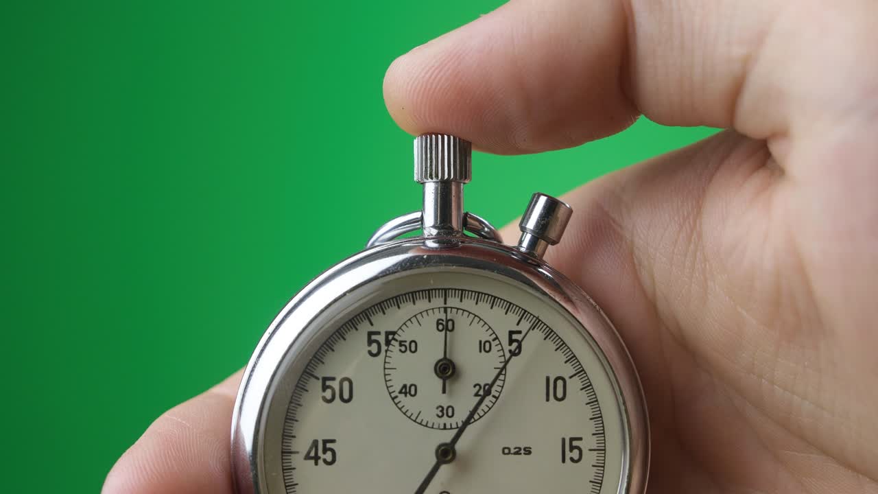 hombre con el reloj analógico en la mano en la pantalla verde llave de croma. tiempo de inicio con el cronometro viejo hombre presiona el botón de inicio en el concepto de deporte. concepto de gestión del tiempo.