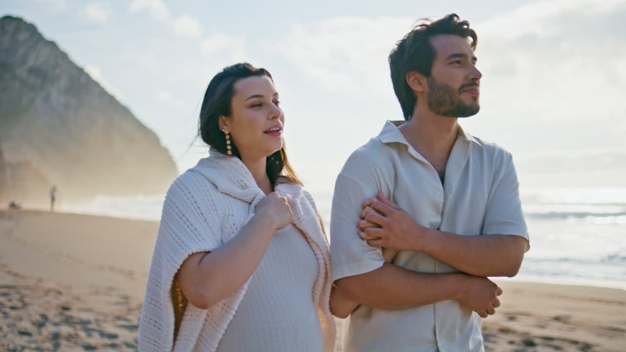 만적 인 임신 한 가족이 해변을 고 있는 바다 풍경 클로즈업. 커플 웃음