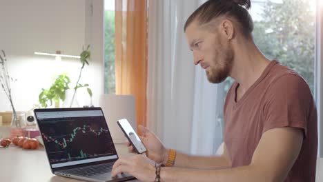 happy man day trading at home on his laptop at the desk while cheering