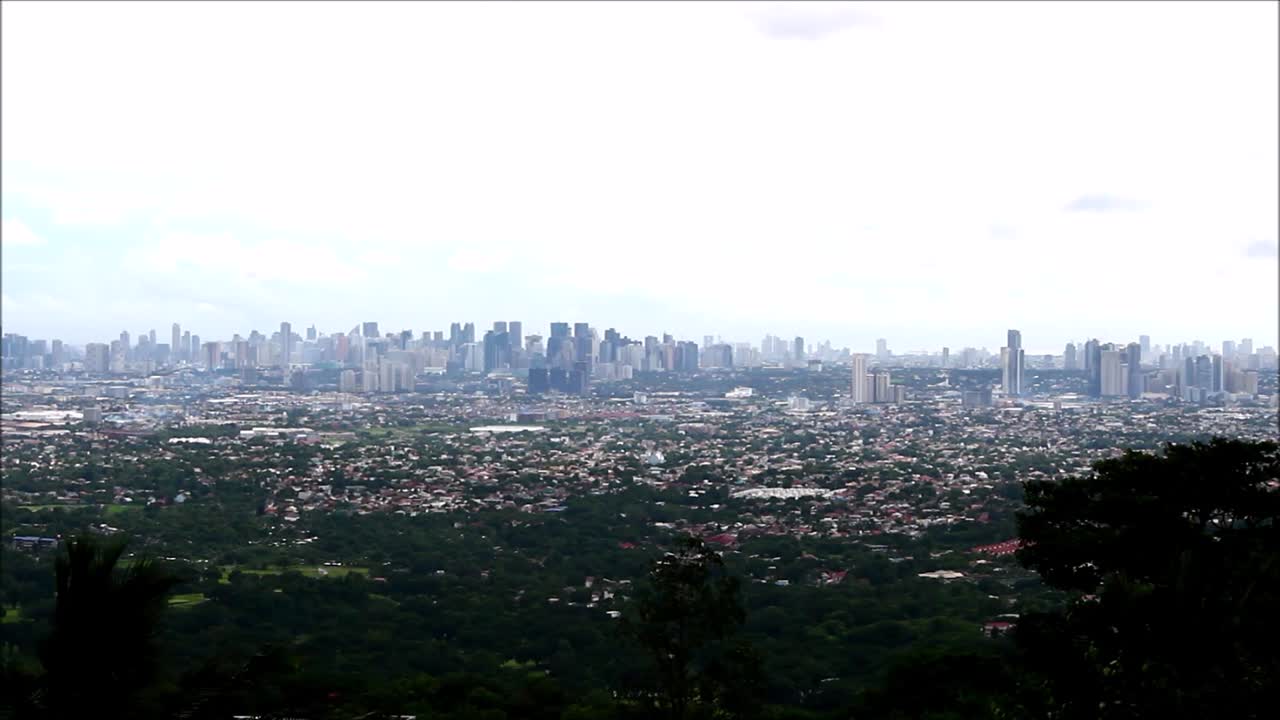Steady extreme long video shot of a cityscape of several towns in Metro Manila, Philippines as seen from a high vantage point on a mountain