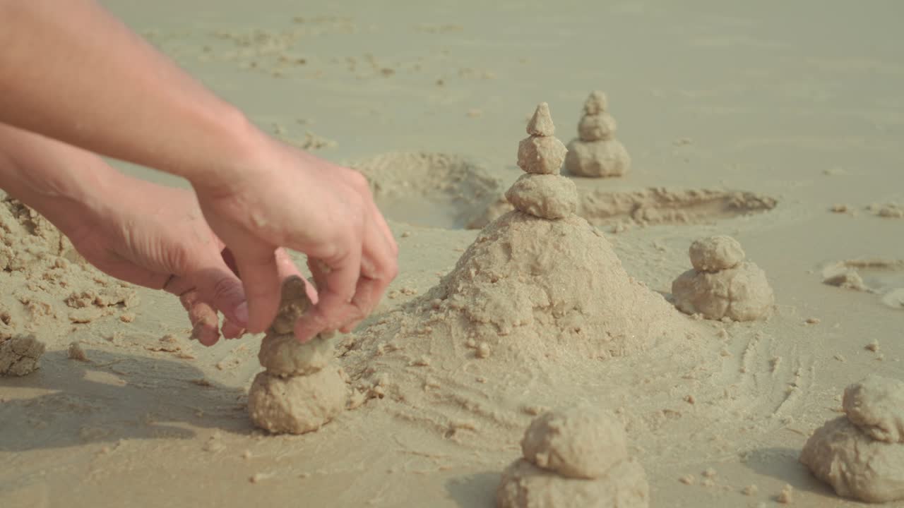 Pequenas torres de areia dispostas na superfície da praia, cena costeira criativa e minimalista.