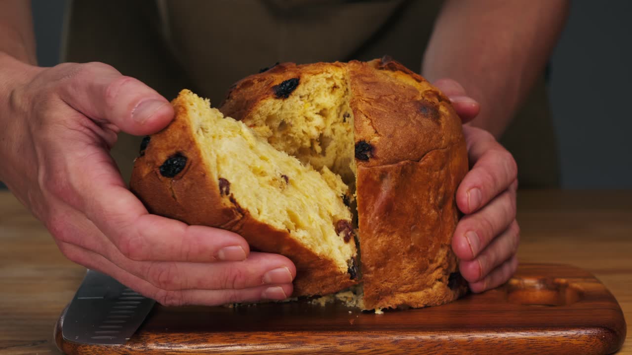 Traditional English Christmas cake tied with a jute thread on the black background. Italian classic Panettone .Pastry Chef sprinkles powdered sugar through a sieve on the fruit Easter cake with raisins. High quality 4k footage
