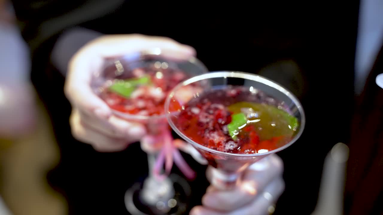 Un cocktail di frutta rossa viene versato da una caraffa in bicchieri da martini guarniti con menta