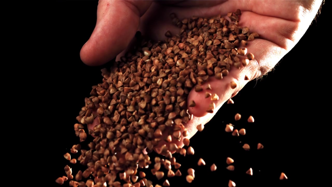 Grano saraceno decorticato che cade da una mano al rallentatore