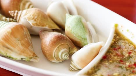 a vibrant assortment of shellfish served with a zesty, colorful dipping sauce on a white platter.