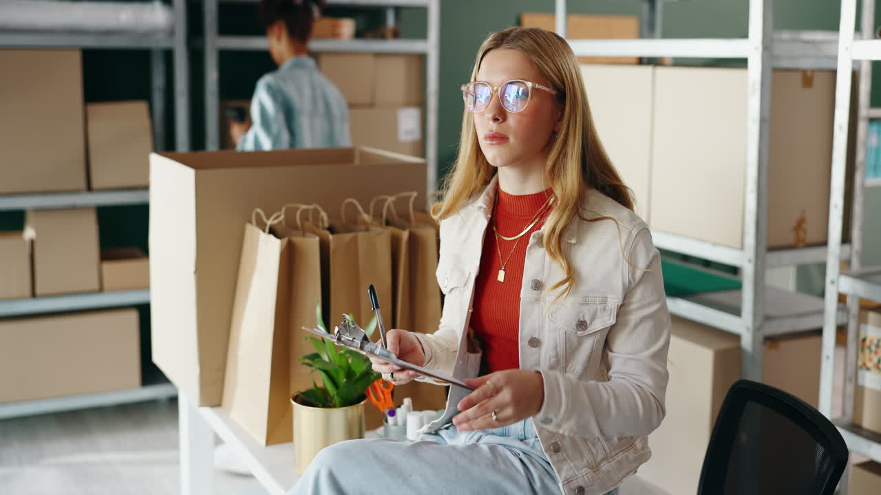 Woman working in warehouse with boxes and clipboard
