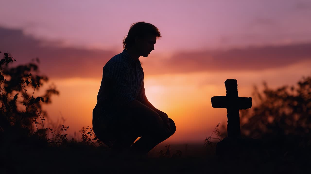 Silhouette solennelle d’une personne agenouillée près d’une croix, sur fond de coucher de soleil à couper le souffle, capturant un moment de recueillement et de deuil dans un paysage serein.