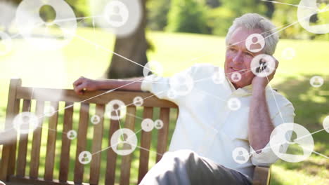 animation of connected icons, senior caucasian man sitting on bench and talking on cellphone at park