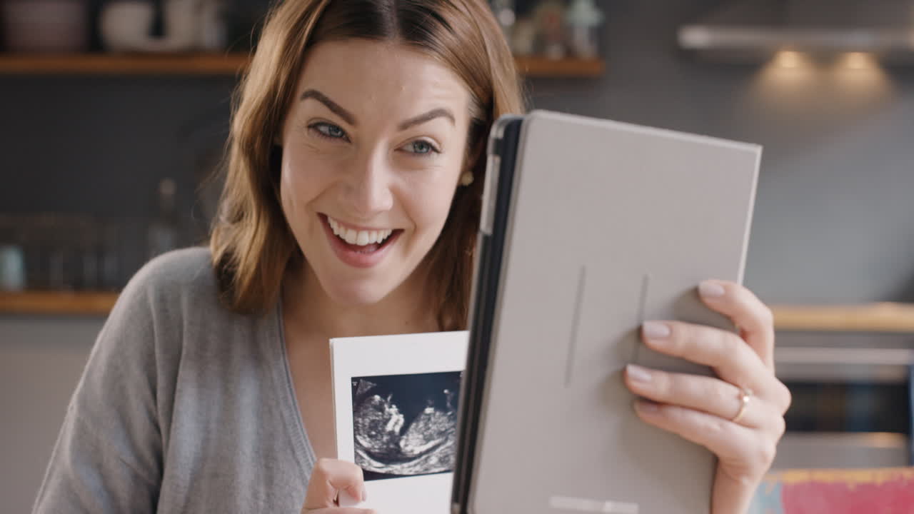 счастливая беременная женщина делится ультразвуком, разговаривая с друзьями по интернету с помощью видео приложения для цифрового планшета