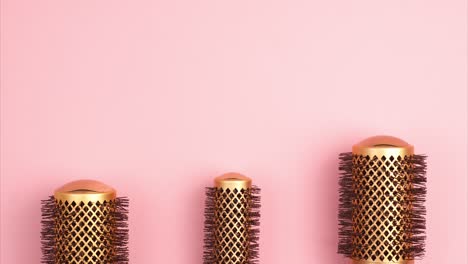 stop motion animation of professional gold round hair brushes for styling at the bottom of the image template with copy space on pink background. hairdresser salon equipment concept, premium set