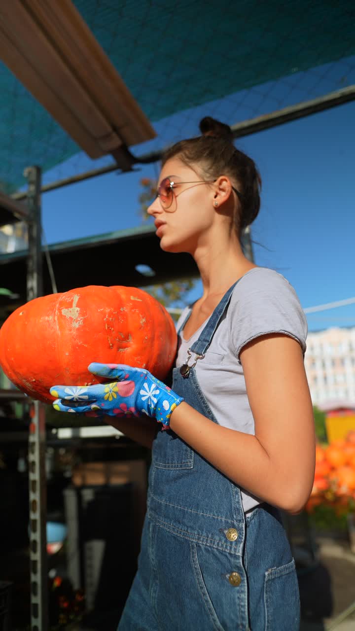 mujer sosteniendo una calabaza en un jardín