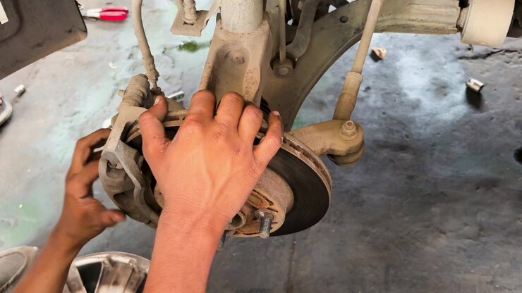 automotive technician checking front brake rotor and caliper in professional repair garage
