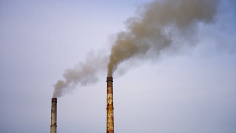 Factory pipes with smoke. Dirty smoke pours out of chimneys into the air on the river background. Aerial view video.