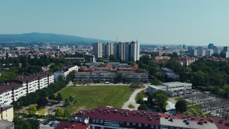 drone shot over Zagreb showing high-rise buildings, dense housing and forest backdrop with mountains
