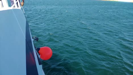 flotador protector colgando del costado del barco navegando con el mar tranquilo y calmado en un día soleado de cielo azul, baleado bloqueado, pontevedra, galicia, españa