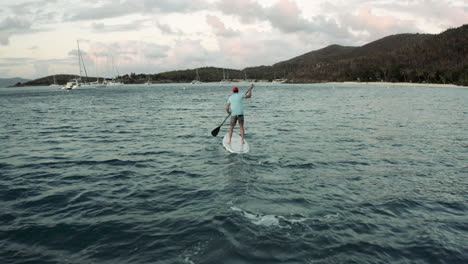 drohne folgt als stand-up-paddle-boarder auf eine hügelige insel in der karibik zu