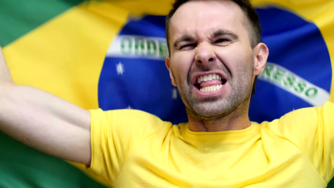 fanático brasileño celebra sosteniendo la bandera de brasil en cámara lenta, 4k, de alta calidad