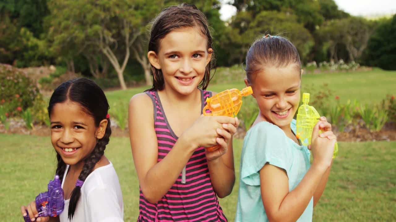 Ritratto di bambine sorridenti che tengono pistole ad acqua