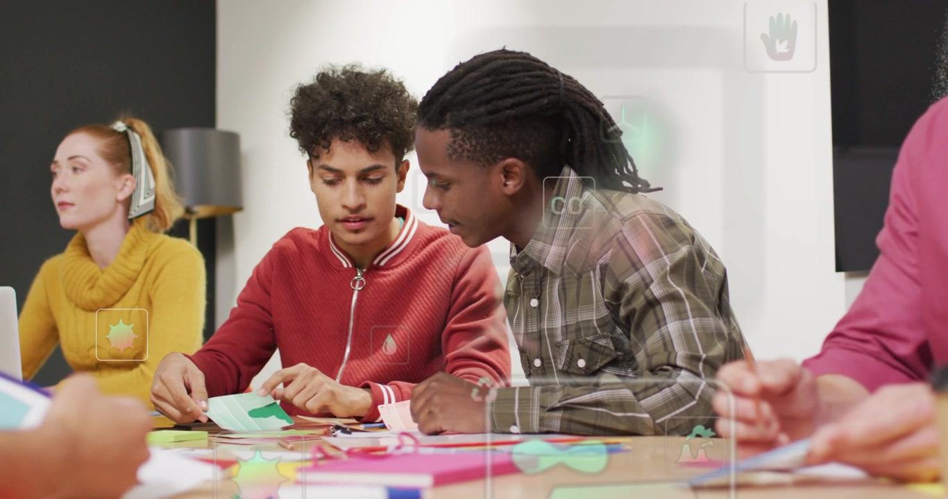Two men sorting paper and folding green piece, leaning in, guiding assembly in craft workshop