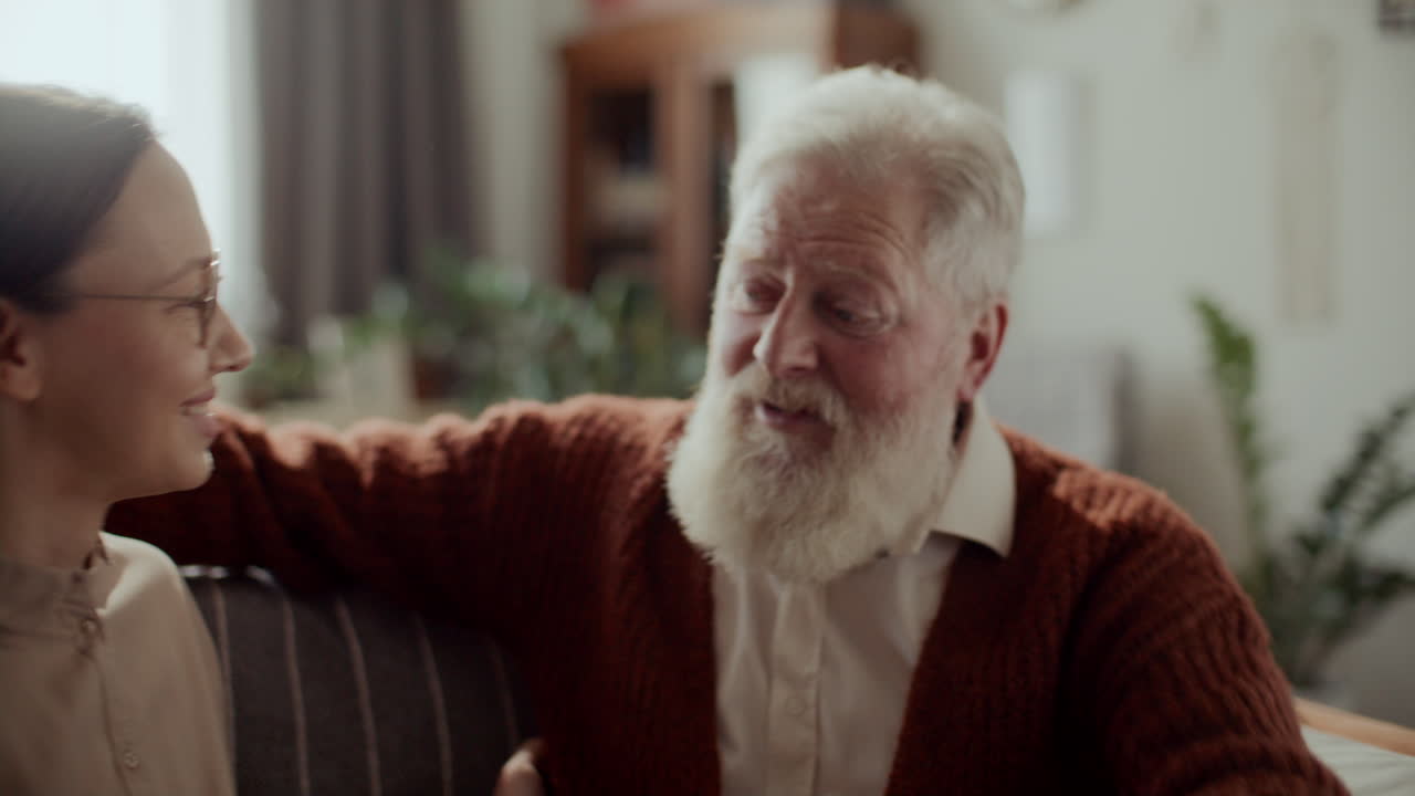 Elderly Man Hugging Granddaughter with Love on Couch at Home