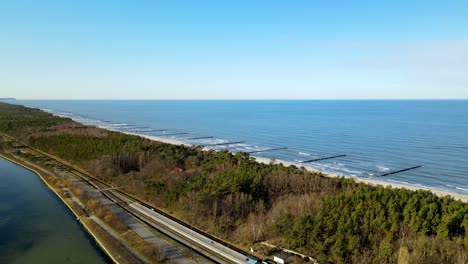 descending aerial shot of magnificent baltic sea and driving cars on narrow road of hel in poland