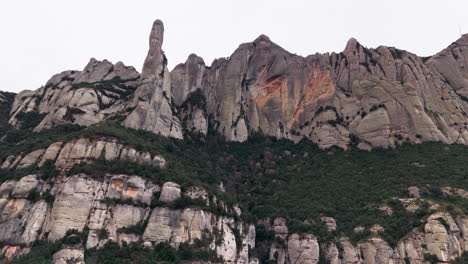 Empuje-épico-De-Drones-En-Una-Toma-De-Grandes-Picos-De-Acantilados-Verdes-En-Un-Tranquilo-Día-Nublado