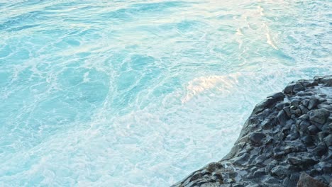 Splashing-water-towards-the-rocks-on-the-seaside,-static-closeup-slow-motion