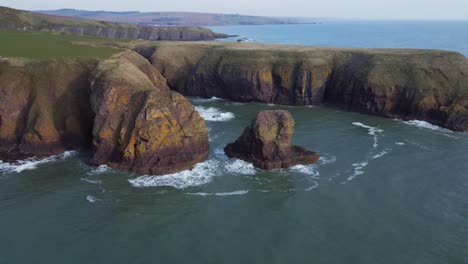 Flying-towards-majestic-cliffs-near-Dunnottar-Castle-in-Scotland-with-birds-gliding-through-the-air-and-powerful-waves-crashing-against-the-rugged-cliffs