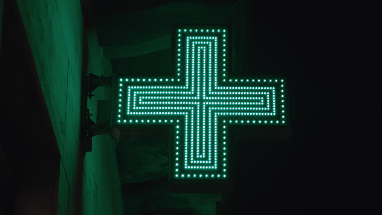 Green Illuminated Pharmacy Cross Sign at Night