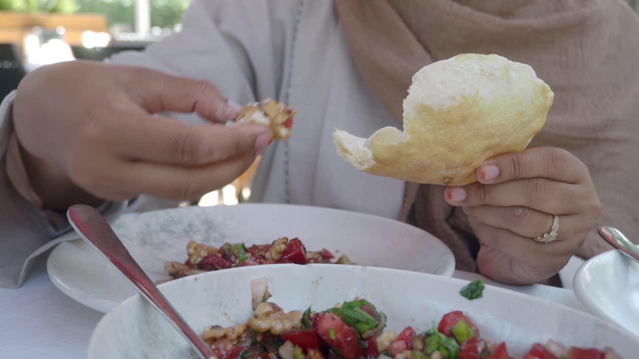 Close-up of a person eating a meal with pita bread and salad