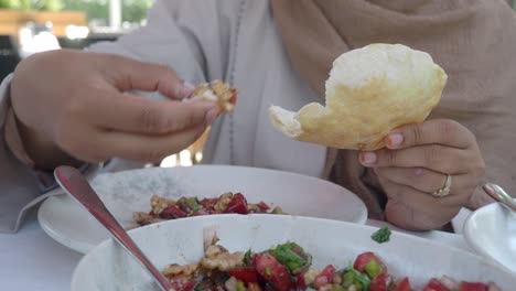 close-up of a person eating a meal with pita bread and salad