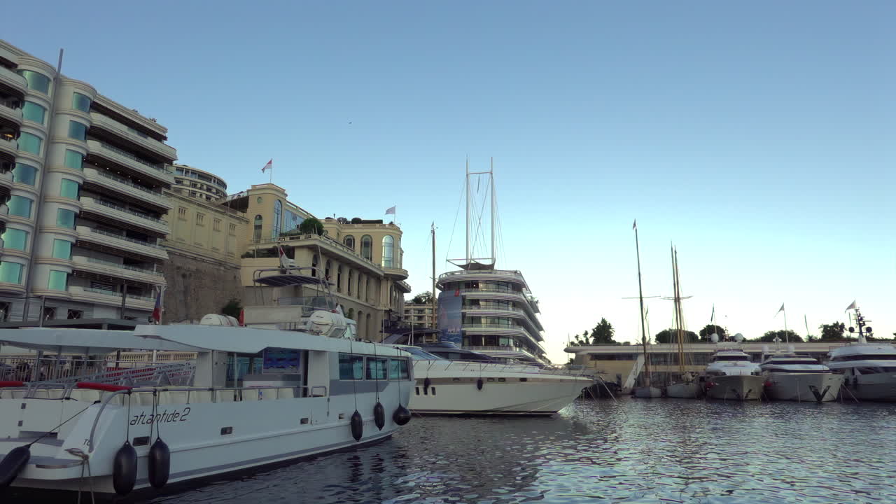 Monte Carlo, Monaco - July 4, 2025: Yachts and launches tied up near the modern tiered Yacht Club building, with luxury residences along the quay