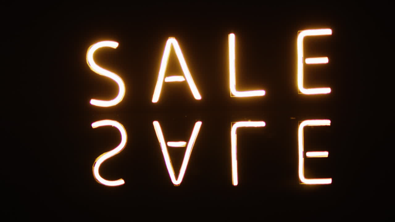 las luces de neón deletrean '' venta '' contra un fondo oscuro