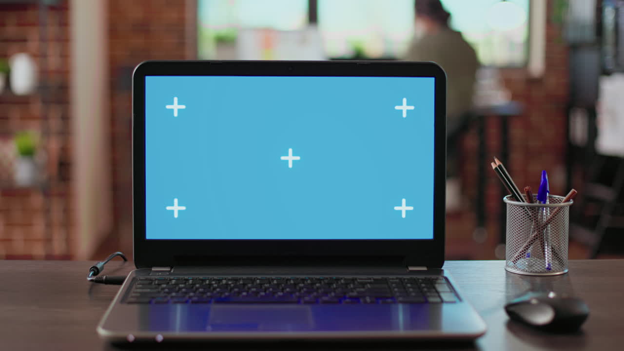 Empty office desk with greenscreen display on wireless laptop