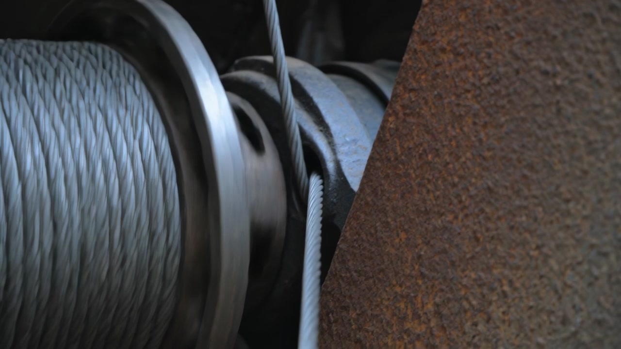 Engaging motor, drum rotating, braided cable sliding into sheave gap to seat cable in equipment bay