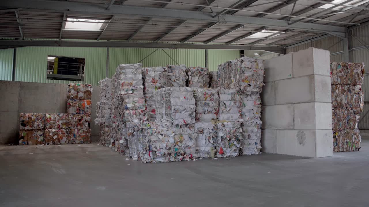 재활용 과정의 핵심 단계인 종이와 카드보드의  ⁇ 을 닫는 비디오 영상입니다. 이 재료들은 압축되고 관리 가능한, 친환경적인 패키지로  ⁇ 여집니다.