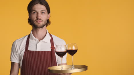 Caucasian-waiter-in-front-of-camera-on-yellow-background.