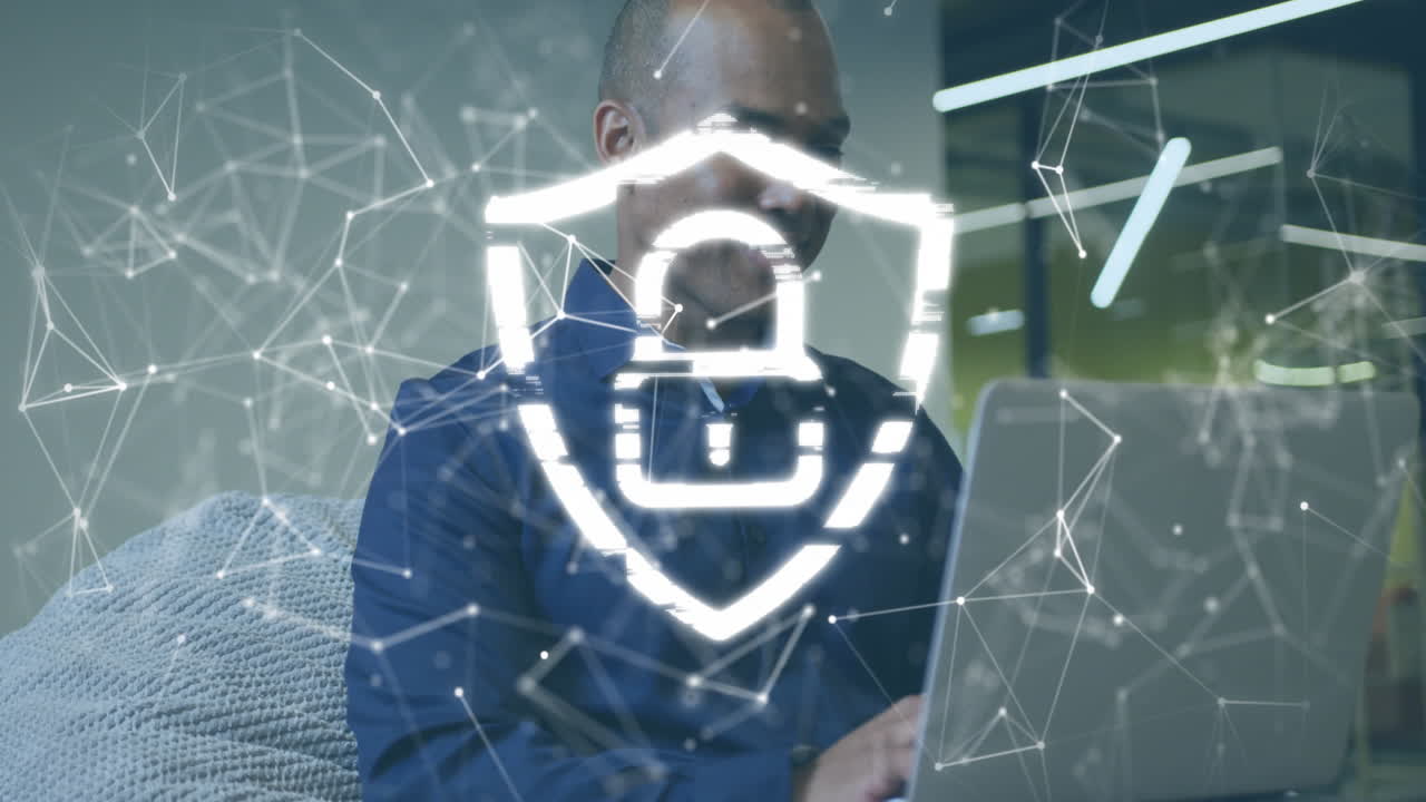 Animation of padlock in shield, connected dots over african american businessman working on laptop